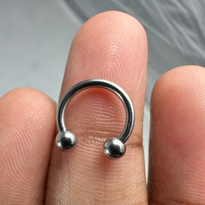May include: A silver horseshoe-shaped body piercing with two round balls on the ends.