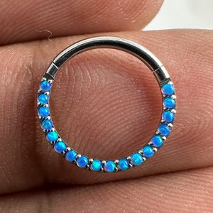 May include: A silver hoop earring with a row of light blue opal stones around the edge.
