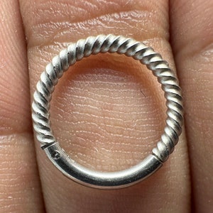 Può includere: Un orecchino a cerchio in argento, intrecciato, con un piccolo accento di diamante.