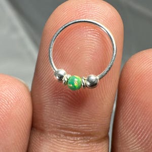 Può includere: Anello per il naso in argento con tre perline, tra cui una perlina di opale verde.
