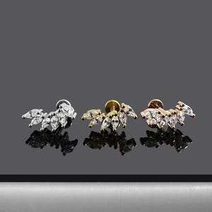 May include: Three silver, gold, and rose gold ear studs with a curved row of clear marquise-shaped stones.