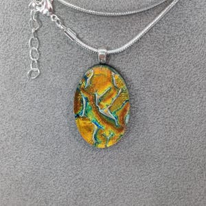 Medium Sized Orange Gold Dichroic Oval Pendant with a Silver-tone Necklace