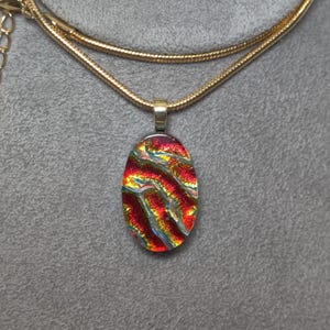 Small Fused Bright Red Dichroic Glass Oval Pendant on Black with a Gold-tone Chain