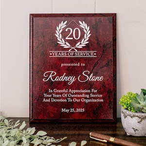 Może przedstawiać: Prostokątna tabliczka z wykończeniem w kolorze ciemnoczerwonego i czarnego marmuru, z białym grawerem o treści 20 Years Of Service, presented to Rodney Stone, In Grateful Appreciation For Your Years Of Outstanding Service And Devotion To Our Organization, May 25, 2025.