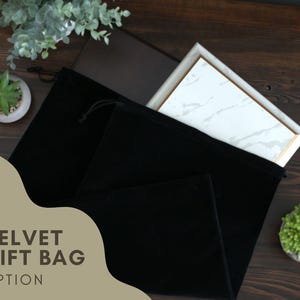 a black velvet gift bag sitting on top of a wooden table