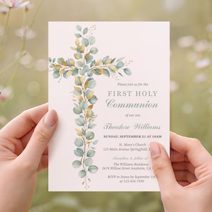 May include: A First Holy Communion invitation card held by hands. The card features a cross design made of green and gold leaves. The text includes the words "First Holy Communion" and the name "Theodore Williams".