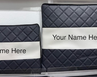 May include: Two navy blue quilted cases with a white band across the center. The smaller case has the text "Name Here" and the larger case has "Your Name Here" in black lettering. Both cases have a black zipper.