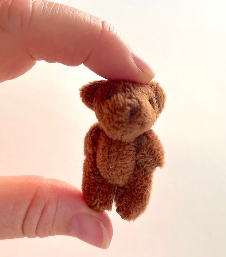 May include: A small brown teddy bear with a soft, plush texture. The bear is standing on its own and has a simple, classic design.
