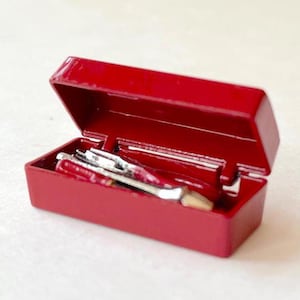 May include: A red metal toolbox with a hinged lid is open, revealing a set of tools inside. The tools include a screwdriver, pliers, and a wrench.