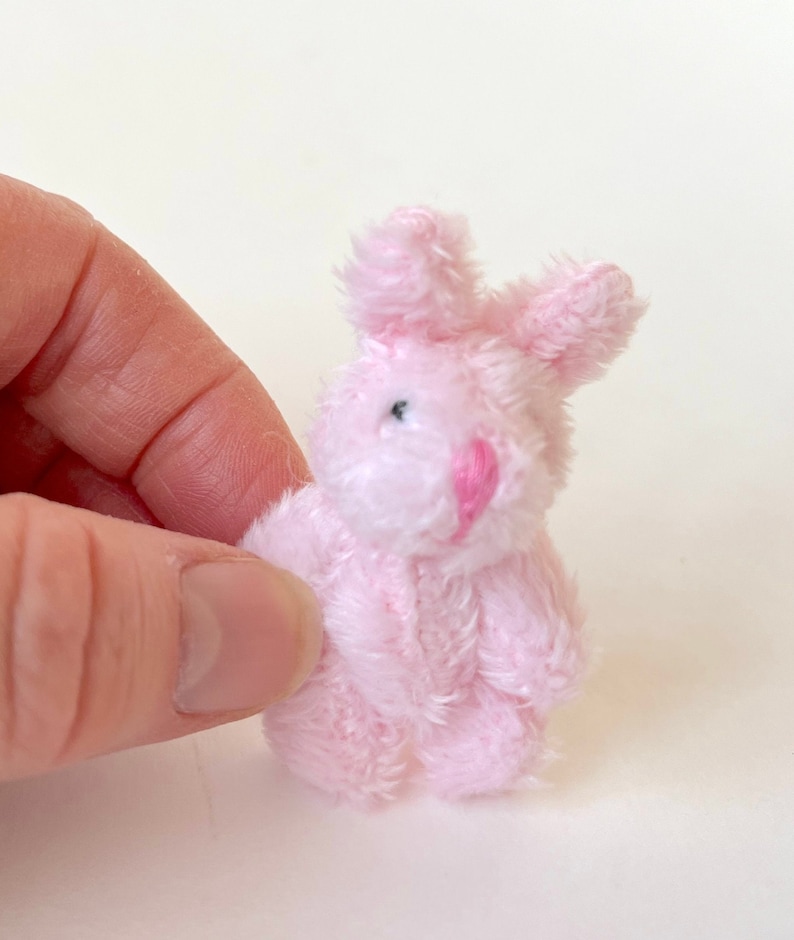 K&ouml;nnte beinhalten: Ein kleines rosa Pl&uuml;sch-Hasenspielzeug. Der Hase hat eine rosa Nase und schwarze Augen.