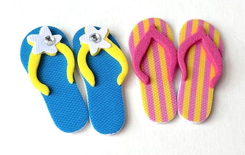 May include: Two pairs of flip-flops, one pair is blue with yellow flowers and the other pair is yellow and pink striped.