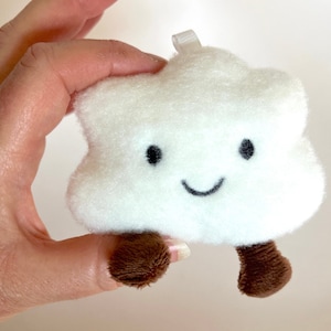 Puede incluir: Nube de felpa blanca con una cara sonriente y pies marrones.