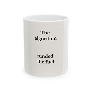 May include: A white ceramic mug with the text "The algorithm funded the fuel" in black. The mug has a simple, cylindrical shape and a clean, minimalist design, suitable for coffee or tea.