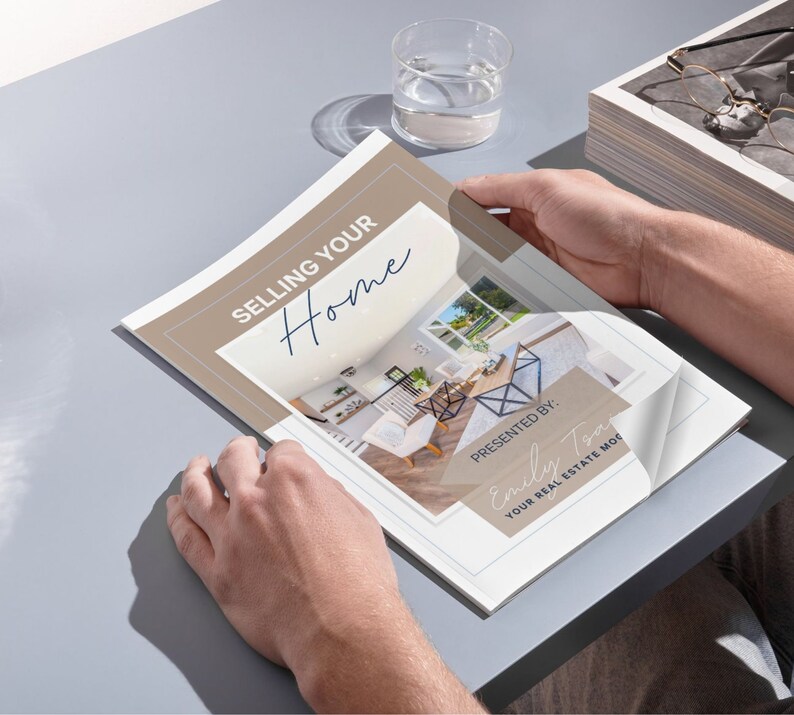 May include: A tan and white brochure with the text "Selling Your Home" in blue script. The brochure is open to a page with a photo of a modern kitchen and dining room. The text "Presented By: Emily Tom Your Real Estate Mom" is in a blue rectangle at the bottom of the page.