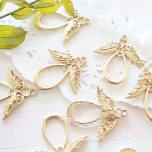 May include: A collection of gold-toned metal angel wing charms with a teardrop-shaped loop. The charms have intricate details and are perfect for jewelry making.