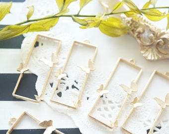 May include: Gold-toned metal frames with butterfly cutouts. The frames are rectangular and have a hole at the top for hanging.