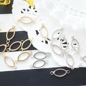 Puede incluir: Una colección de anillos de metal ovalados de color dorado y plateado con anillos de salto. Los anillos están dispuestos sobre un fondo de encaje blanco.