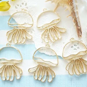 Può includere: Sei pendenti in metallo a forma di medusa di colore dorato. I pendenti sono trasparenti e hanno una finitura liscia. Sono perfetti per la fusione di resina o altri progetti di artigianato.