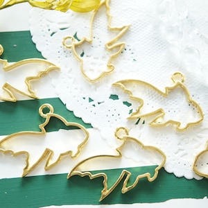 Può includere: Bianchi per ciondoli in metallo dorato a forma di pesce. I bianchi sono vuoti e hanno un anello nella parte superiore per essere attaccati a una catena o un cordino.