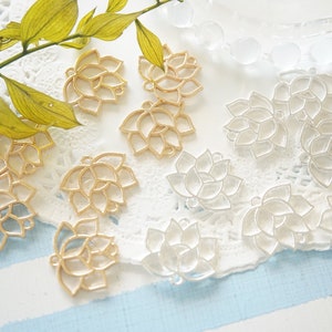 May include: A collection of gold and silver metal charms shaped like lotus flowers. The charms have a delicate, openwork design and are perfect for adding a touch of elegance to jewelry or crafts.