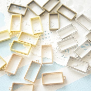 Puede incluir: Surtido de bandejas rectangulares de vidrio para colgantes con marcos de metal en dorado, plateado y bronce. Las bandejas son perfectas para manualidades con resina, elaboración de joyas y otros proyectos de bricolaje.