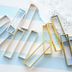 Op de afbeelding: Assortiment van rechthoekige metalen frames in zilver, goud en brons. De frames zijn ontworpen voor het gieten van hars en hebben een beugel om op te hangen.