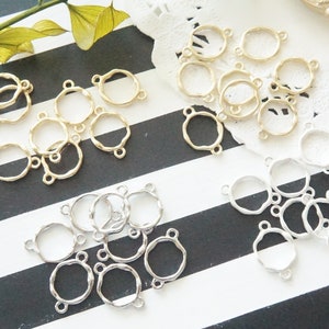 May include: A collection of gold and silver metal connector rings with a wavy edge. The rings have three holes for attaching jewelry components.
