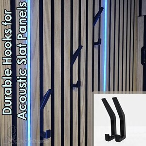 May include: Black metal hooks fixed to a wooden slat panel. The panel features vertical stripes of light and dark wood. The text "Durable Hooks for Acoustic Slat Panels" is visible. A small inset shows two hooks.