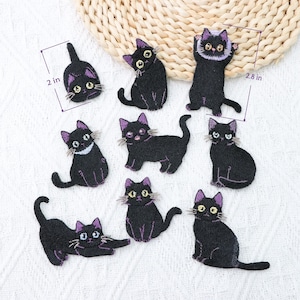 Könnte beinhalten: Eine Sammlung von acht bestickten Aufnähern in Form schwarzer Katzen mit violetten Akzenten an Ohren und Schwänzen. Die Katzen sind in verschiedenen Posen dargestellt, darunter sitzend, streckend und stehend. Zwei Aufnäher zeigen Maßlinien von 5,08 cm und 7,11 cm.