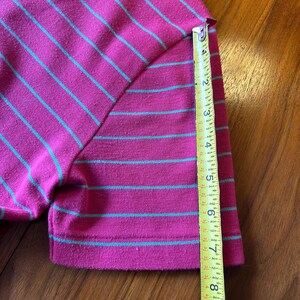 Może przedstawiać: Koszulka polo w paski r&oacute;żowe i zielone z taśmą mierniczą pokazującą długość rękawa 17,8 cm.