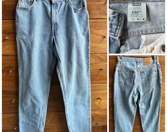 May include: Light blue denim jeans with a relaxed fit and tapered leg. The jeans have a high waist and are made by Levi's. The label on the jeans reads "550 Relaxed Fit Tapered Leg 10  MIS M".