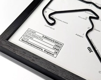 May include: A black and white illustration of a race track with the name "Silverstone" and details about the track, including its length, first Grand Prix, opening date, and number of turns. The track is located in Northamptonshire, England.