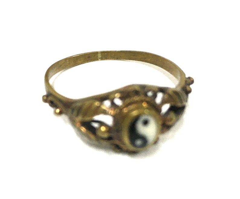 Peut inclure: Une bague en or avec un design complexe repr&eacute;sentant un symbole yin yang noir et blanc.