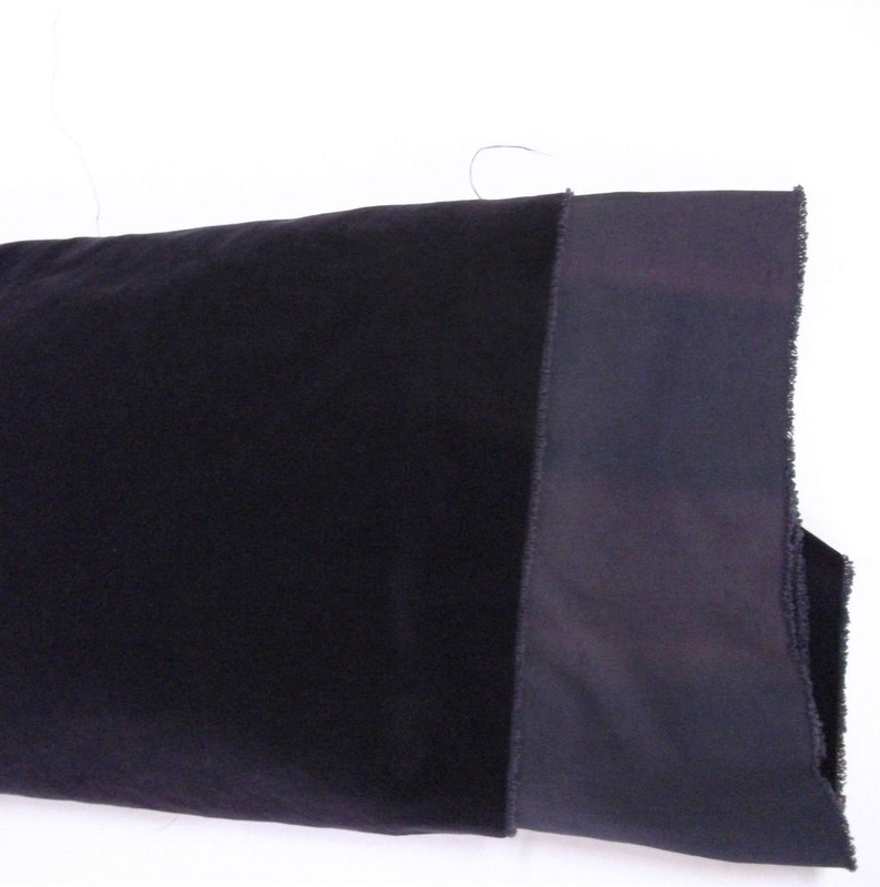 Pu&ograve; includere: Primo piano di un tessuto blu scuro con un bordo nero a contrasto. Il tessuto ha una texture morbida e vellutata.