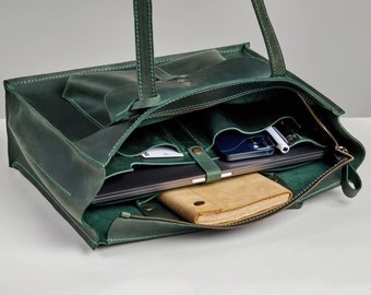 May include: A green leather tote bag with a bow detail on the front. The open bag reveals a laptop, a notebook, a smartphone, and other items. The bag has a zipper closure and multiple interior pockets.
