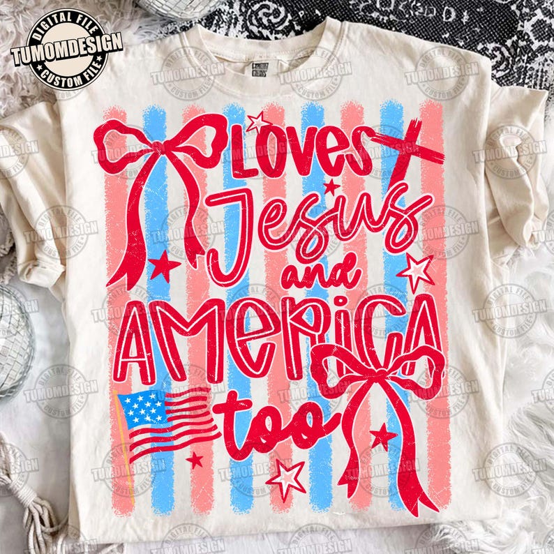 May include: Cream-colored t-shirt with a patriotic design. The shirt features red and blue vertical stripes, red bows, stars, and the text "Loves Jesus and America too" in red script. An American flag is also included.