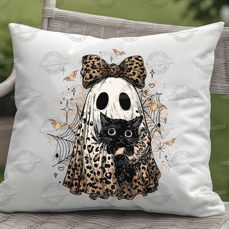 May include: White square pillow featuring a Halloween-themed design. A ghost with a leopard print bow and cape is holding a black cat. The design includes bats, spiderwebs, and stars. The pillow is a decorative item.