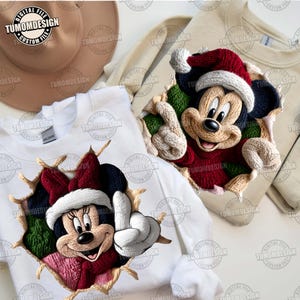 May include: White sweatshirts featuring Mickey and Minnie Mouse in Christmas attire. The designs appear to be bursting through the fabric, with Mickey wearing a red Santa hat and Minnie wearing a red bow and hat. The text "TUMOMDESIGN" is visible.