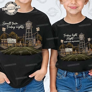 Puede incluir: Dos camisetas negras con un gráfico de un campo de fútbol americano de noche, una torre de agua, luces de estadio y un marcador que muestra 47567. La camiseta izquierda dice Small town Friday nights y la derecha Friday light Night small town, big dreams.