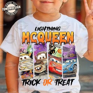 May include: A white t-shirt featuring a graphic print of four cartoon cars dressed in Halloween costumes. The text reads LIGHTNING MCQUEEN at the top and TRICK OR TREAT at the bottom. The cars are depicted as a mummy, a monster, a vampire, and a witch.