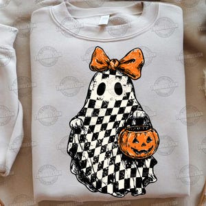 K&ouml;nnte beinhalten: Ein hellgraues Sweatshirt mit einem Halloween-Geist-Design. Der Geist ist schwarz-wei&szlig; kariert, mit einer orangefarbenen Schleife und einem K&uuml;rbis. Eine lustige und festliche Wahl f&uuml;r die gruselige Jahreszeit.