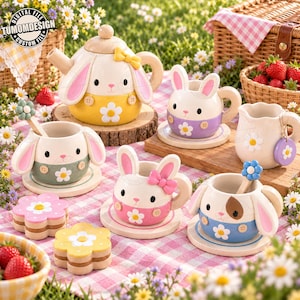 May include: A tea set featuring a teapot and four cups shaped like rabbits with long ears, each wearing a colored base with a white flower. The set includes matching saucers, two flower-shaped spoons, and two flower-shaped cookies. Text reads TUMOMDESIGN.