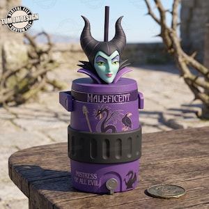 Puede incluir: Un enfriador de bebidas morado con un adorno 3D de un personaje con cuernos negros y piel pálida. El enfriador muestra el texto MALEFICENT y MISTRESS OF ALL EVIL, junto con gráficos de un dragón, un bastón y un cuervo. Una pajita sobresale arriba.