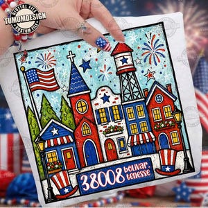 May include: A white t-shirt featuring a colorful illustration of a patriotic town scene. The design includes an American flag, fireworks, and buildings in red, white, and blue. The text "38008 bolivar. tenesse" is also visible.