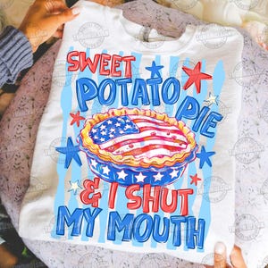 May include: White sweatshirt with a graphic design featuring a sweet potato pie with an American flag design. The text reads "Sweet Potato Pie & I Shut My Mouth" in red and blue. The design includes stars and stripes.