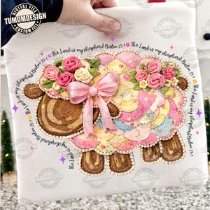 May include: A decorative sheep design with a floral crown and a pink bow. The sheep is made of patchwork fabric in pastel colors, with the text "The Lord is my shepherd Psalm 23:1" around the border. The design is labeled "TUMOMDESIGN".