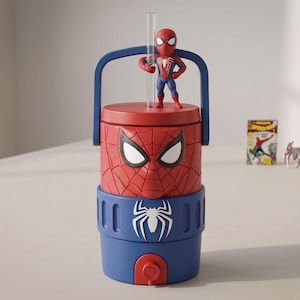Pode incluir: Um dispensador de bebidas cilíndrico com o tema Spider-Man, apresentando um topo vermelho com padrão de teia e uma base azul. Uma pequena figura do Spider-Man está sobre a tampa ao lado de uma palhinha transparente. A secção azul inclui um logótipo de aranha branco.