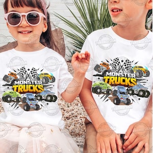K&ouml;nnte beinhalten: Zwei Kinder tragen wei&szlig;e T-Shirts mit einem farbenfrohen Monster-Truck-Motiv. Das Design zeigt verschiedene Monster Trucks in Orange, Gelb, Gr&uuml;n und Blau, zusammen mit Schachflaggen und den Worten "MONSTER TRUCKS".
