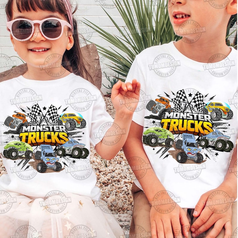 K&ouml;nnte beinhalten: Zwei Kinder tragen wei&szlig;e T-Shirts mit einem farbenfrohen Monster-Truck-Motiv. Das Design zeigt verschiedene Monster Trucks in Orange, Gelb, Gr&uuml;n und Blau, zusammen mit Schachflaggen und den Worten "MONSTER TRUCKS".