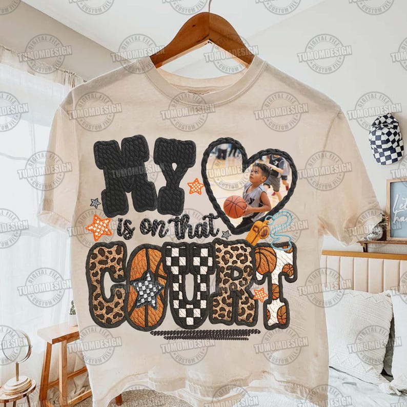 May include: A cream-coloured t-shirt with the text "MY is on that COURT" in various fonts and patterns, including leopard print and basketball imagery. A heart-shaped photo of a child holding a basketball is featured.